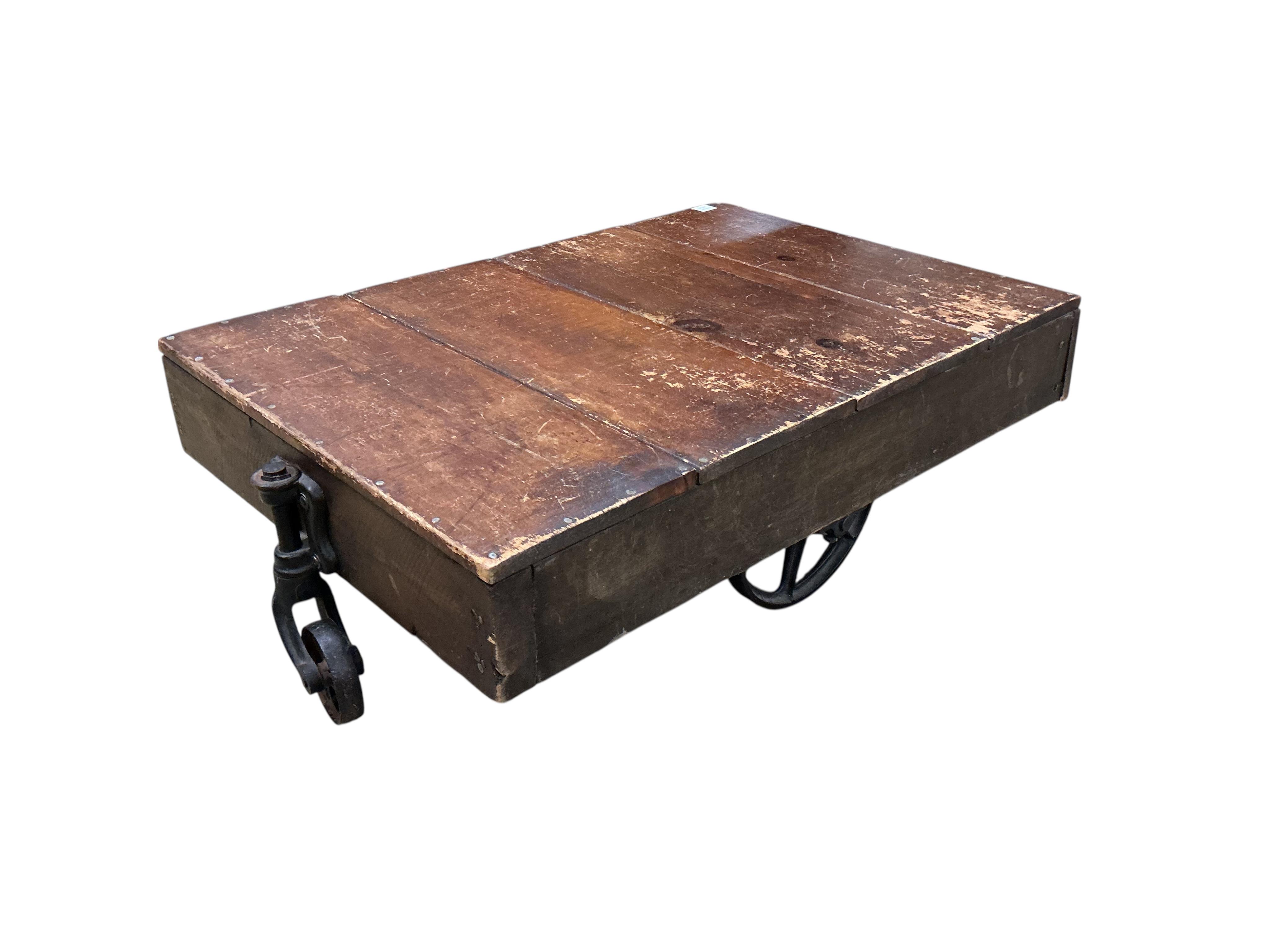 A vintage rectangular wood factory cart with iron spoked wheels now as a coffee table, width 112cm, depth 76cm, height 35cm